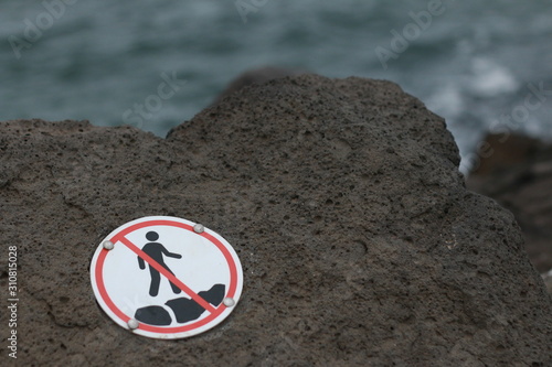 warning signage attached to seaside large rocks warning the public against climbing on the rocks of the wavebreakers in the bay Coastal Melbourne, Victoria, Australia