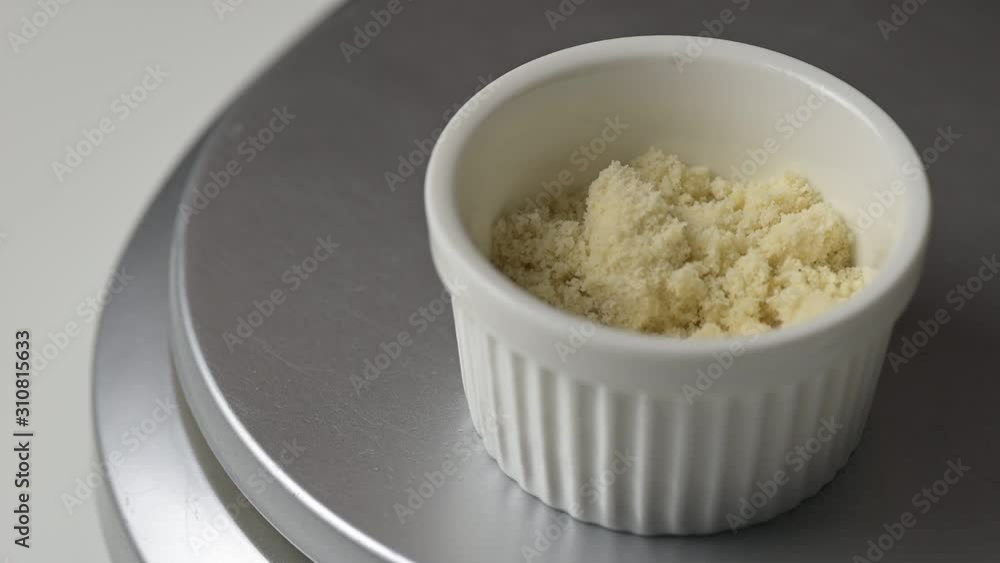 Measuring almond powder in a small white ramekin on a digital scale.