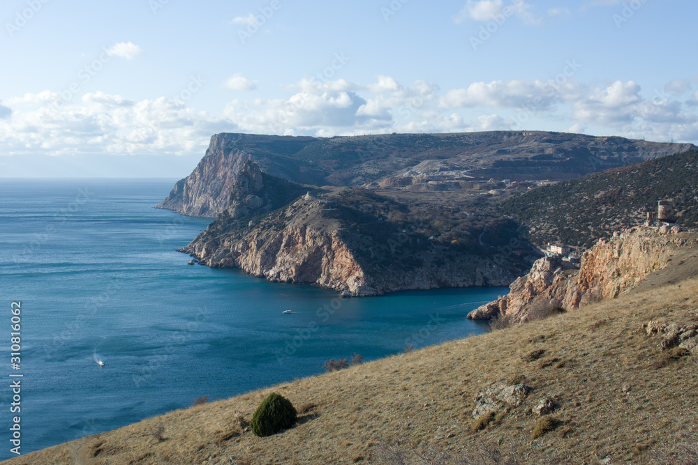 blue sea coast surrounded by big rocks and blue sky with white clouds