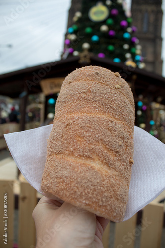 Trdelník is a kind of spit cake, made from rolled dough that is wrapped around a stick, then grilled and topped with sugar and walnut mix. National food in the Prague Christmas market.
