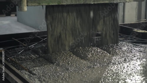 A large radio-controlled machine fills the concrete in form. Workers in the workshop of the House-building plant. Industrial interior. Concrete plant.