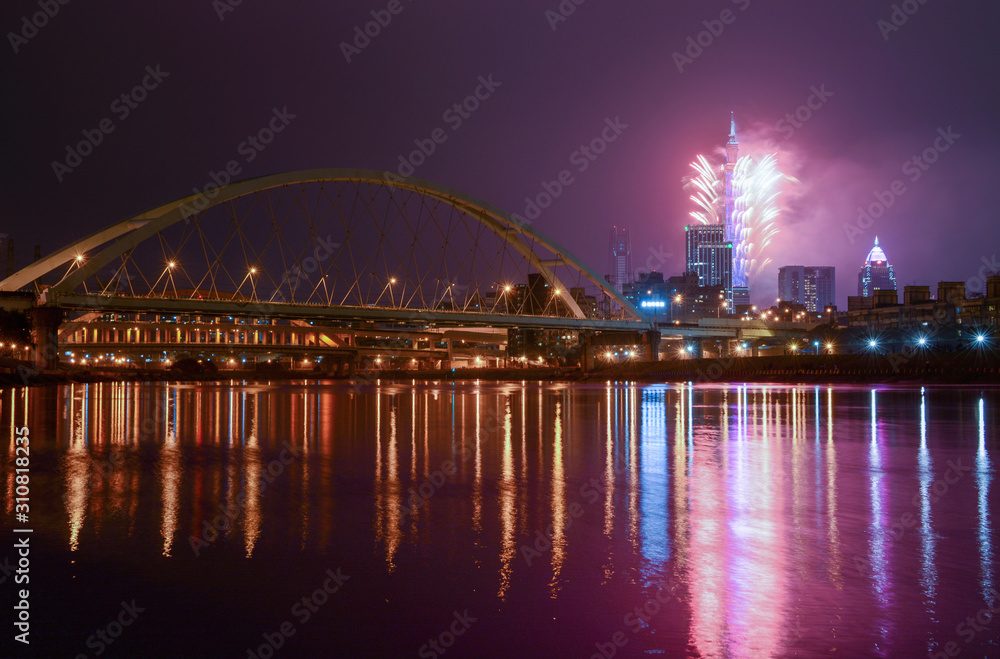 New Year fireworks light up the Taipei City skyline, casting reflections in the Keelung River