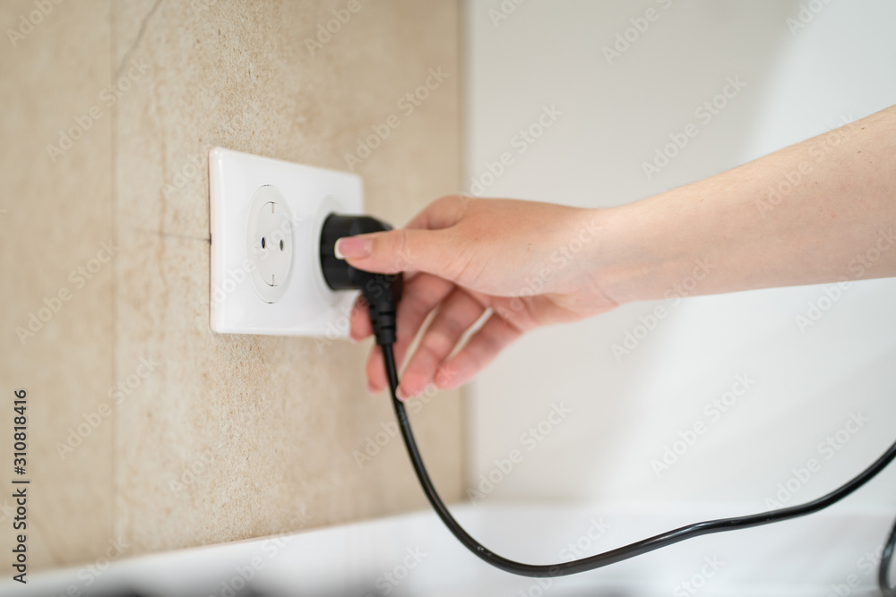 Close up Woman hand insert or pull out elecrticity plug in outlet on the wall Close up Woman hand insert or pull out elecrticity plug in outlet on the wall