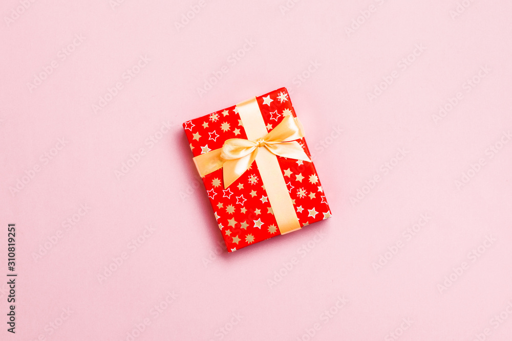 wrapped Christmas or other holiday handmade present in paper with Gold ribbon on pink background. Present box, decoration of gift on colored table, top view with copy space wrapped Christmas or other holiday handmade present in paper with Gold ribbon on pink background. Present box, decoration of gift on colored table, top view with copy space