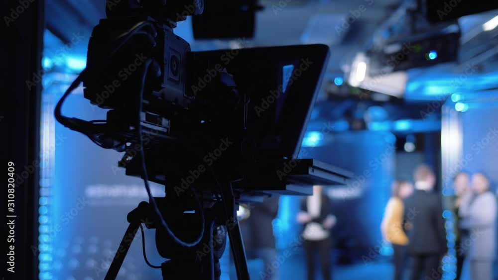 TV camera with commutation equipment stands on tripod in news studio