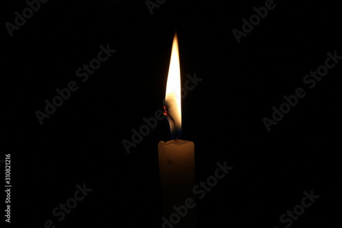 One light candle burning brightly in the black background