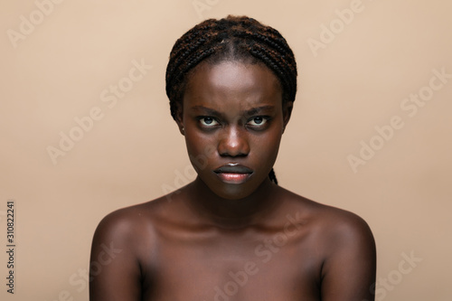 Beautiful young woman touching her face skin and feel the softness with copy space. Smiling girl feeling skin face after beauty treatment. Portrait of african woman looking at camera.