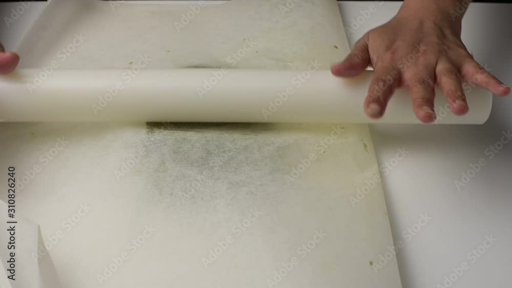 Rolling a green tea cookie dough between two baking paper. Rolling a green tea cookie dough between two baking paper.