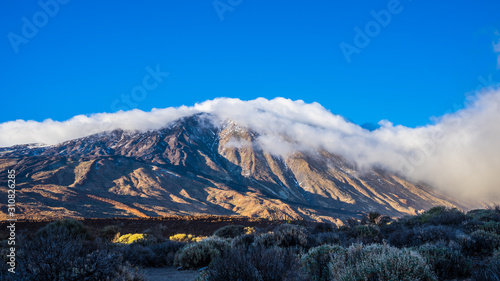 Spain, Tenerife, Volcanic mountain teide with blue sky and covered by fog clouds on sunny day in winter in caldera, a magical nature landscape