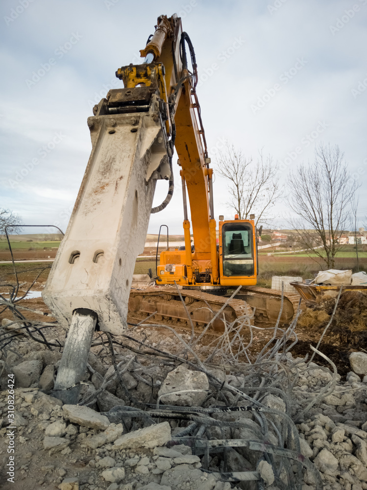 Fototapeta premium Close-up of a hydraulic breaker of a yellow excavator working on