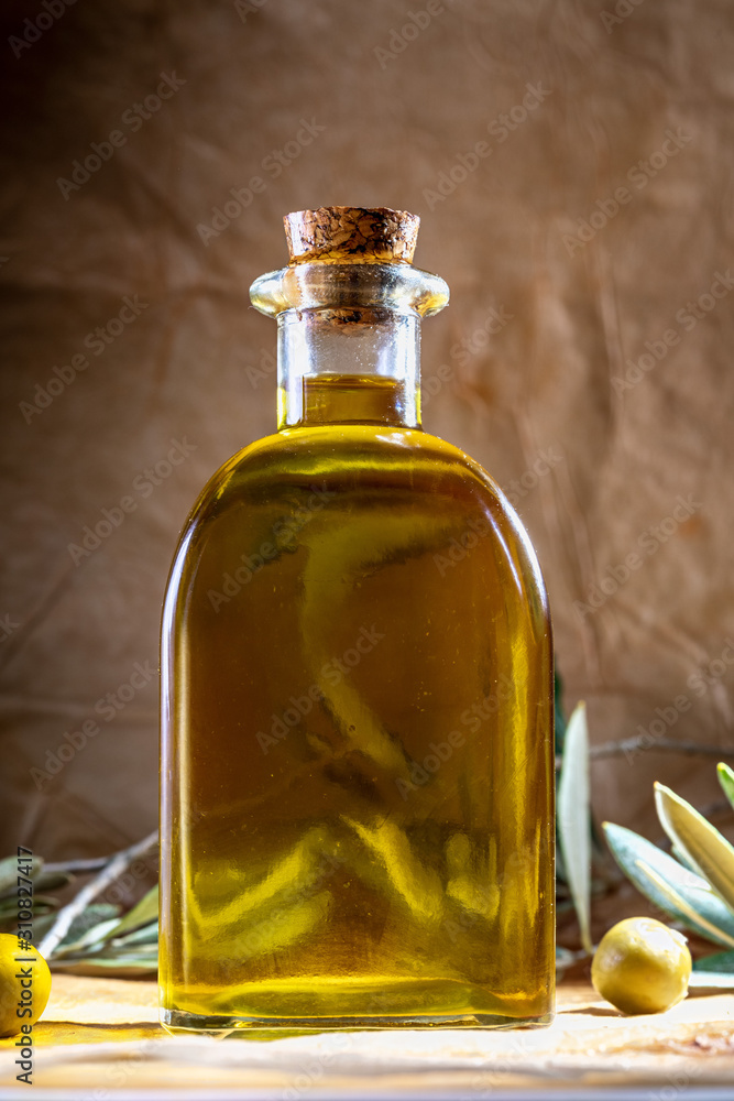Extra virgin olive oil in glass bottle. It includes olive leaves and branches. Rustic Background. Front view. Extra virgin olive oil in glass bottle. It includes olive leaves and branches. Rustic Background. Front view.