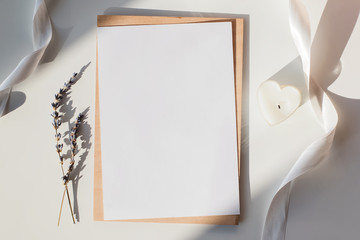 Paper mock-up on the table with white ribbon, lavender and heart shaped candle in natural sunlight with shadows.
