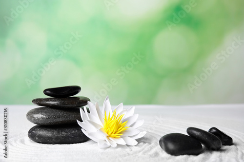 Zen garden. Beautiful lotus flower and stones on white sand, space for text