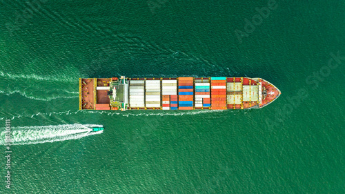 Aerial veaw a Large container ship is leaving the port full loaded with containers and cargo.