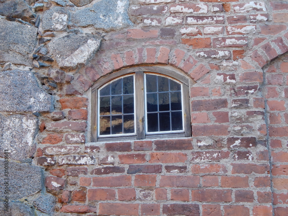 Wall of a medieval castle of stone and brick and a window in it