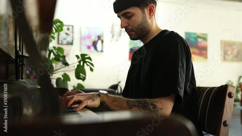 Slow motion of young man sitting in front of old wooden piano and playing