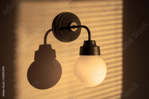 Slika na platnu Lighted classic sconce of round shape on the wall, with soft light and diffused