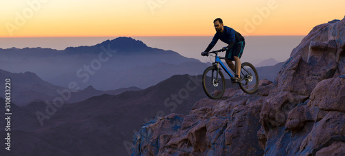 Conquering mountain peaks by cyclist in shorts and jersey on a modern carbon hardtail bike with an air suspension fork . Beautiful view from the mountain. Panoramic view for banner.