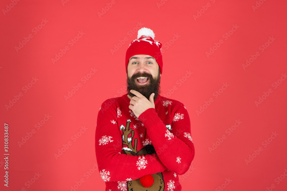 The Joy of Giving. winter clothes fashion. festive holiday atmosphere. portrait of happy santa man. bearded man in hat red background. mature hipster beard in knitted sweater. get warm in cold season