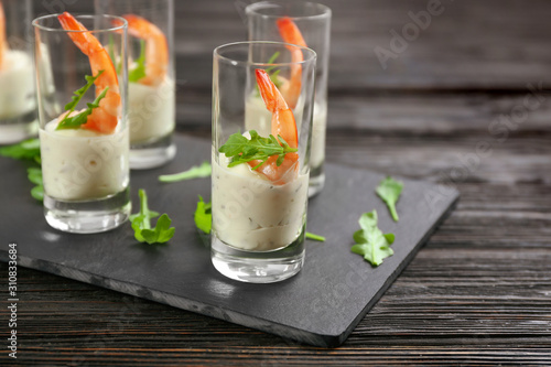 Delicious shrimp cocktail with tartar sauce served on black wooden table