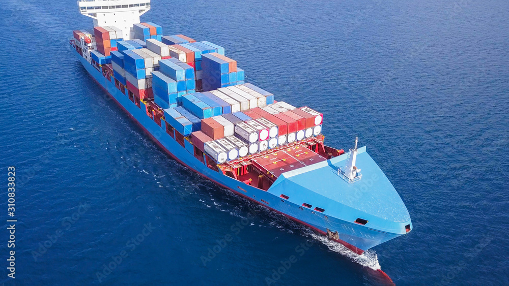 Large container ship at sea, loaded with various container brands. ULCV container ship sails on open water fully loaded with containers and cargo.