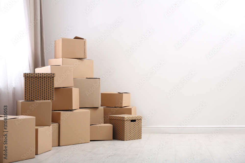 Pile of moving boxes in empty room, space for text Pile of moving boxes in empty room, space for text