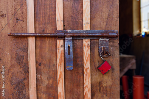 Old red padlock on a wooden door.