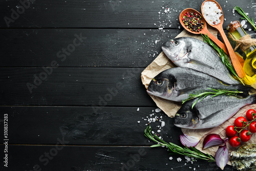 Raw dorado fish with lemon and spices on a black background. Top view. Free space for your text.