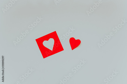 Little red paper heart and red frame with shape of heart on the light grey background. Saint Valentine s Day concept.  © Elena