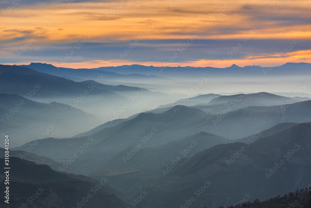 Obraz premium Winter landscape of the Sierra Nevada natural park at sunset with fog banks between the mountains.