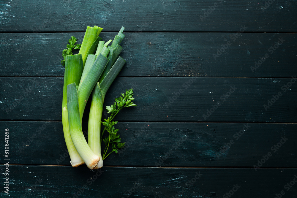 Raw green leek on black background. Vegetables for healthy eating. Top view. Free copy space. Raw green leek on black background. Vegetables for healthy eating. Top view. Free copy space.