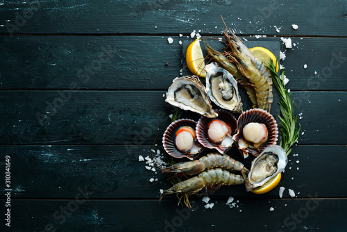 Seafood. Oysters, scallops, shrimp. Top view. On a black background. Free copy space. photo