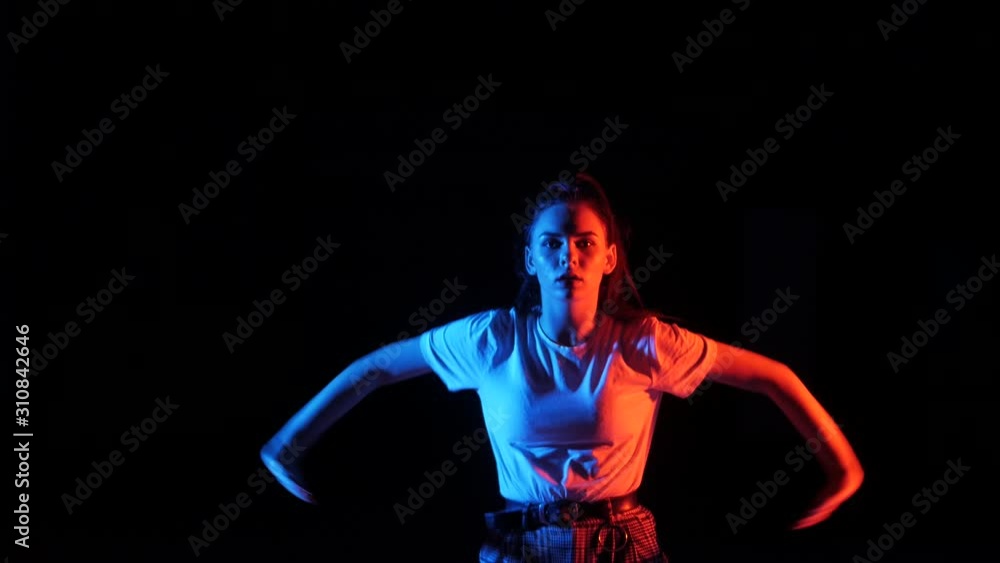 young beautiful girl dancing vogue, street dancing in the studio on a black background, isolated