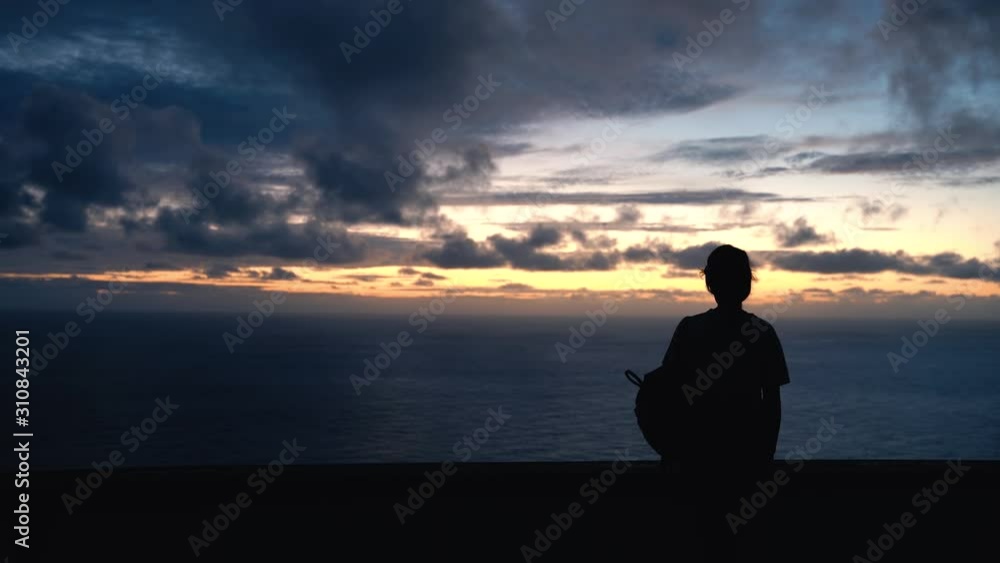 Silhouette of young woman watching a sunset over ocean, Medium shot Silhouette of young woman watching a sunset over ocean, Medium shot