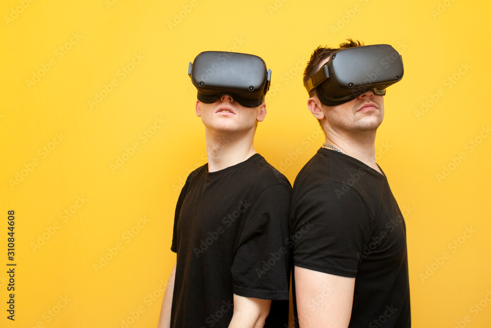 two guys in VR glasses on a yellow background, a pair of friends of gamers in virtual reality glasses two guys in VR glasses on a yellow background, a pair of friends of gamers in virtual reality glasses