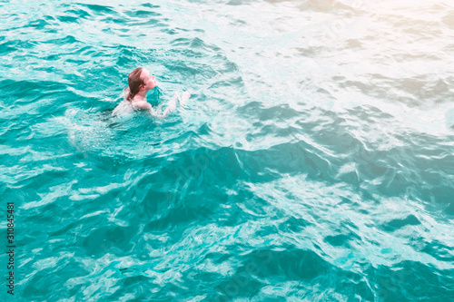 Young woman in blue water, aerial view. Sexy girl relaxing in sea captured from drone. Tropical summer vacation. Tranquility and peace. Person floating on back in ocean. Stock photography. © Nataliya
