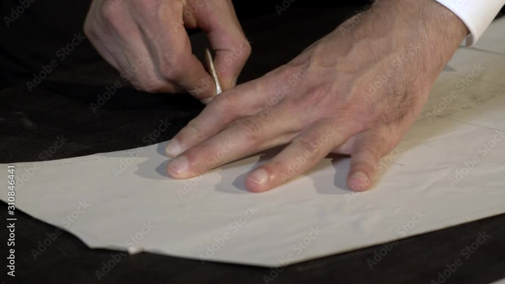 A tailor is drawing lines on a fabric with his chalk in order to make a suit A tailor is drawing lines on a fabric with his chalk in order to make a suit