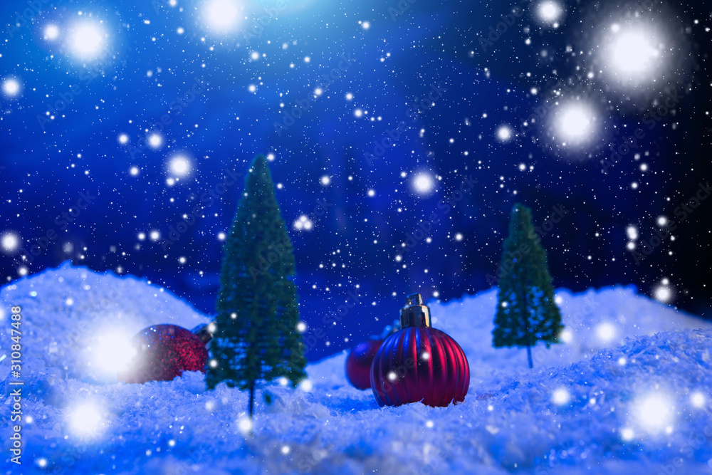 Fototapeta premium Christmas background with Christmas balls on snow over fir-tree, night sky and moon. Shallow depth of field. Christmas background. Fairy tale. Macro. Artificial magic dreamy world.