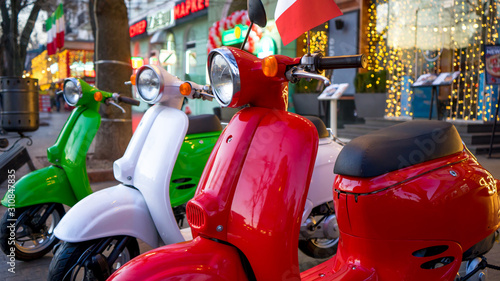 Fototapeta Naklejka Na Ścianę i Meble -  Retro vintage scooters stand near an Italian restaurant. Modern personal transport.