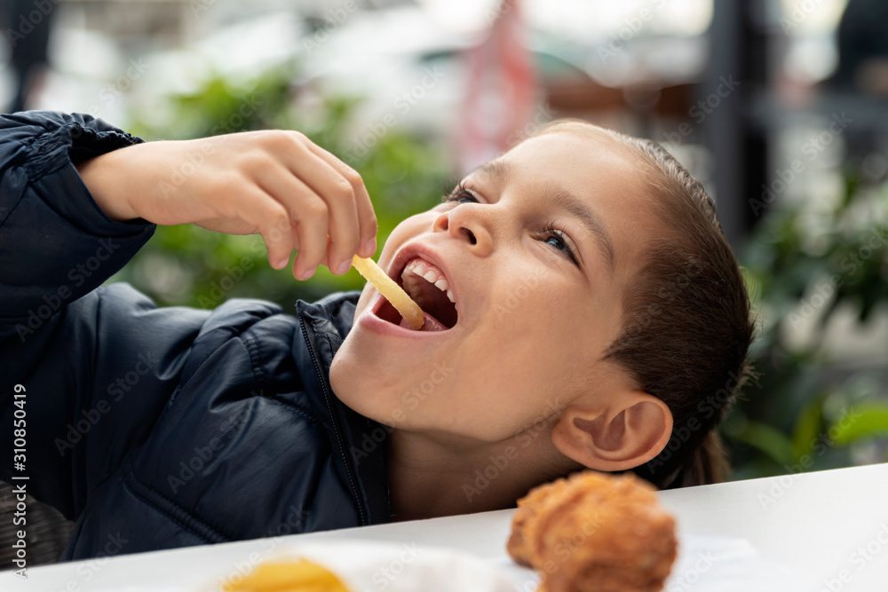 Obraz premium little boy eats french fries and chicken