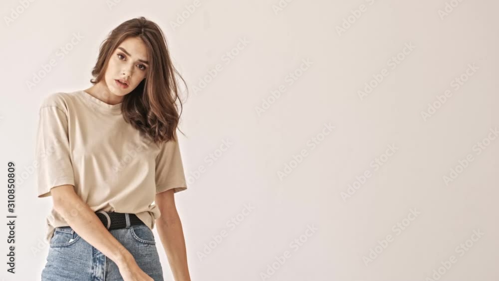 Carefree beauty brunette woman actively posing and looking at the camera over grey background Carefree beauty brunette woman actively posing and looking at the camera over grey background