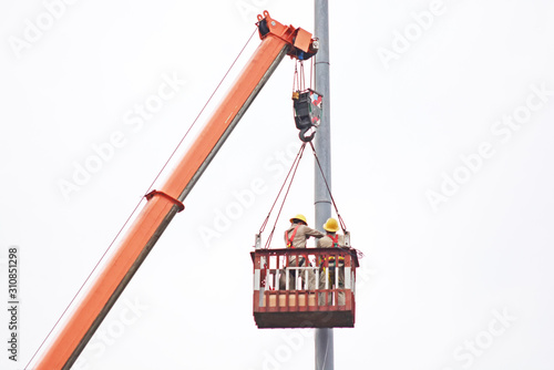 Staff with security hat on the crane lift up to fix the post