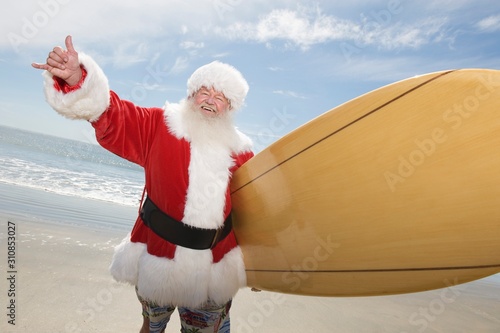 Photography Santa Claus Gesturing With Surf Board On Beach