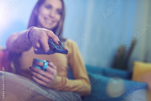 Foto Woman holding a remote control and watching TV