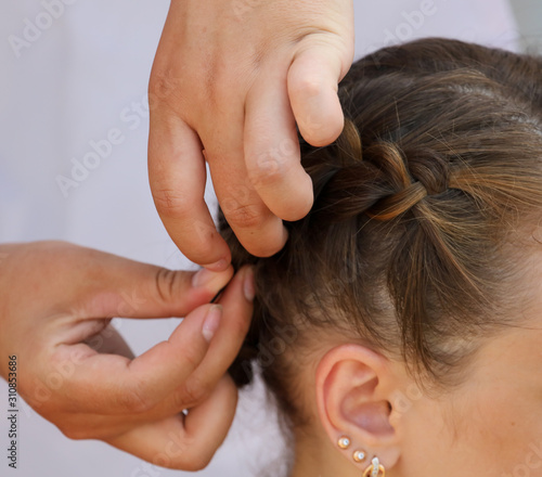 Braiding braids on the head of a girl in the salon