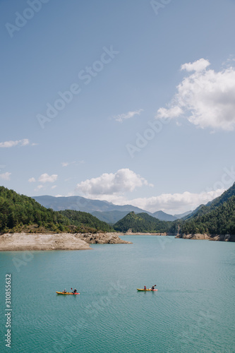 People practicing sport (kayak) on a sunny day in a blue water lake surrounded by mountains on summer © lasfotosdexus