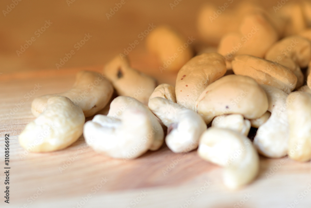 Cashew nuts scattered on a wooden surface close-up. Healthy food background. Brown color toned Cashew nuts scattered on a wooden surface close-up. Healthy food background. Brown color toned