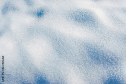 White snow texture on the sun. Winter snowy background of fresh snow with hills surface in blue tone.
