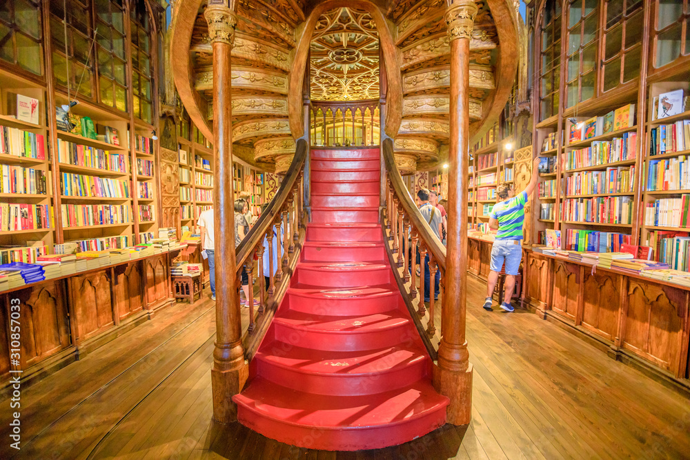 Obraz premium Oporto, Portugal - August 13, 2017: large wooden staircase with red steps inside Library Lello and Irmao in historic center of Porto, famous for Harry Potter film. Horizontal shot.