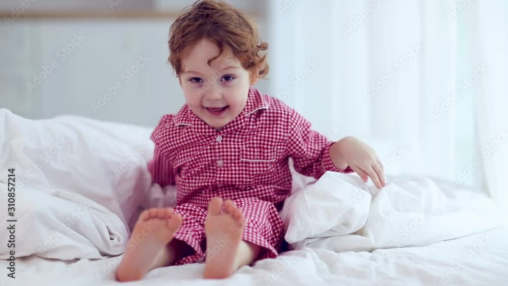 cute happy little boy, kid playing peekaboo, hiding under the blanket on the bed cute happy little boy, kid playing peekaboo, hiding under the blanket on the bed